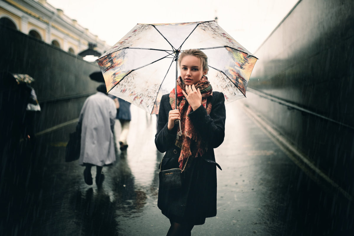 a-girl-in-black-cloak-wiht-umbrella-walking-along-a-road-on-a-rainy-day-by-Ivan-Proskurin